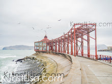 Lade das Bild in den Galerie-Viewer, Blick-auf-roten-Aussichtspunkt-mit-fliegenden-Möwen-am-Meer-im-Hafen-in-Peru-Architekturfotografie
